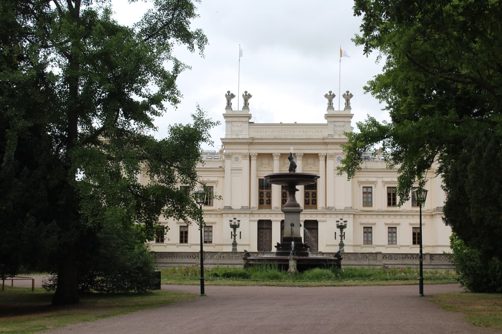 Das Hauptgebäude der Universität Lund hinter dem Brunnen im Lundagård-Park